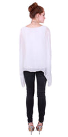 Woman wearing a white sheer long-sleeve blouse and black skinny jeans, rear view