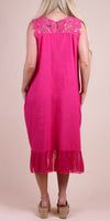 Back view of woman wearing sleeveless pink linen dress with lace yoke and ruffle hem