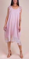 Woman in a light pink linen dress with lace sleeves and sheer ruffle hem, neutral background