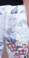 White drawstring pants with floral and script print, featuring pink and gold flowers and lavender motif.