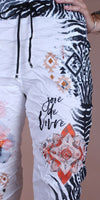 White drawstring pants with black zebra stripes, tribal geometric prints, and 'joie de vivre' text