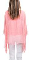 Back view of woman wearing a sheer pink silk blouse and white pants
