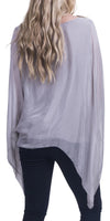 Back view of woman wearing light grey sheer silk blouse with batwing sleeves and black pants