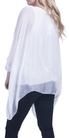 Woman wearing a loose white sheer poncho top with batwing sleeves and black pants