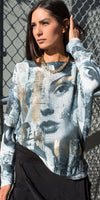 Woman wearing graphic face print sweater and gold chain necklace outdoors