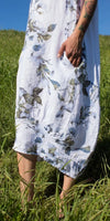 White linen floral dress with pockets, worn outdoors in a grassy field
