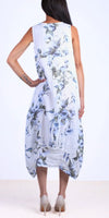Back view of woman wearing sleeveless white floral linen dress and nude heels