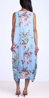 Woman wearing a sleeveless light blue floral linen dress, shown from the back, with sandals