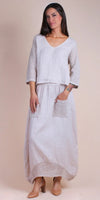 Woman wearing light linen maxi dress with crochet sleeves and pockets, neutral background