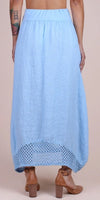 Back view of a woman wearing a light blue linen maxi skirt with crochet hem detail
