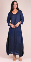 Woman wearing a navy blue linen maxi dress with crochet sleeves and front pockets