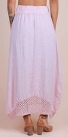 Back view of a light pink linen midi skirt with crochet lace hem, worn with tan block heels.