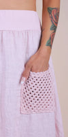 Light pink linen skirt with crochet pocket detail and a tattooed arm resting on the pocket