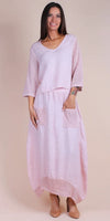 Woman wearing a light pink linen maxi dress with crochet sleeves, pockets, and hem detail.