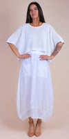 Woman wearing white linen eyelet top and matching midi skirt with front pockets
