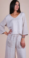 Woman wearing a beige linen set with crochet sleeves and pockets, relaxed fit, v-neck top