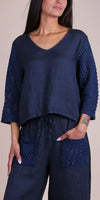 Woman wearing navy linen top with crochet sleeves and matching pants with crochet pockets