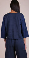 Back view of woman wearing navy linen top with crochet sleeves and matching pants