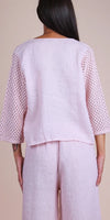 Back view of woman in light pink linen outfit with crochet sleeves and wide-leg pants
