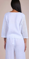 Back view of woman wearing white linen top with crochet sleeves and matching wide-leg pants