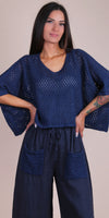 Woman wearing navy crochet knit top with wide sleeves and navy linen pants with crochet pockets