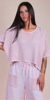 Woman wearing a light pink crochet knit top and matching linen pants with crochet pockets