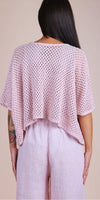 Back view of a woman wearing a light pink crochet knit top and pink linen pants