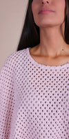 Close-up of woman wearing a light pink crochet knit top with open weave texture