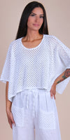 Woman wearing white crochet knit top and loose linen pants with crochet pockets