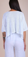 Woman in white crochet knit top and linen pants, back view, minimalist neutral background