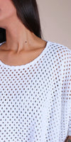 Close-up of woman wearing a white open-knit crochet top with wide neckline