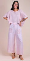 Woman wearing pink crochet knit top and wide-leg linen pants with front pockets