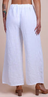 Back view of woman wearing white linen wide-leg pants with elastic waistband and block heels