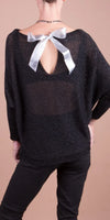 Black sheer sweater with open back and silver bow detail, modeled by woman