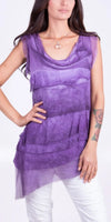 Woman wearing a sleeveless purple layered tunic top with white pants
