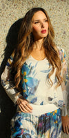 Woman wearing floral print silk blouse and skirt set in natural sunlight