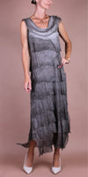 Woman wearing sleeveless gray layered maxi dress with asymmetrical hem and white heels