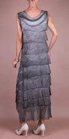 Back view of woman wearing sleeveless tiered grey maxi dress with sheer layers and white heels