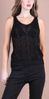 Woman wearing sleeveless black knit tank top and black pants against neutral background