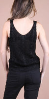 Woman wearing black knit sleeveless top and black pants, shown from the back