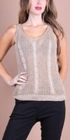 Woman wearing a sleeveless beige knit tank top with cable knit details and black pants