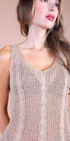 Woman wearing a beige open-knit cable sleeveless top, close-up view, neutral background