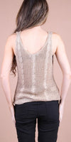 Woman wearing a beige knitted sleeveless top with cable detailing, shown from the back