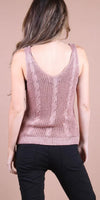 Woman wearing a pink knit sleeveless top with cable details and black pants, back view