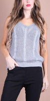 Woman wearing a light gray sleeveless knit top with cable detailing, paired with black pants