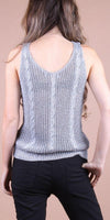 Back view of woman wearing a light gray cable knit sleeveless top and black pants