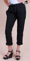 Woman wearing black drawstring linen pants with cuffed ankles and black wedge sandals