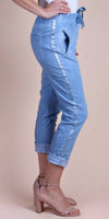 Light blue cropped pants with metallic side stripes, tie waist, and rolled cuffs on model