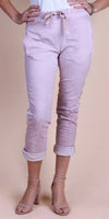 Light pink linen pants with drawstring waist and rolled cuffs, worn with heels