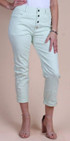 Woman wearing light mint high-rise button fly pants with cuffed hems and nude heels